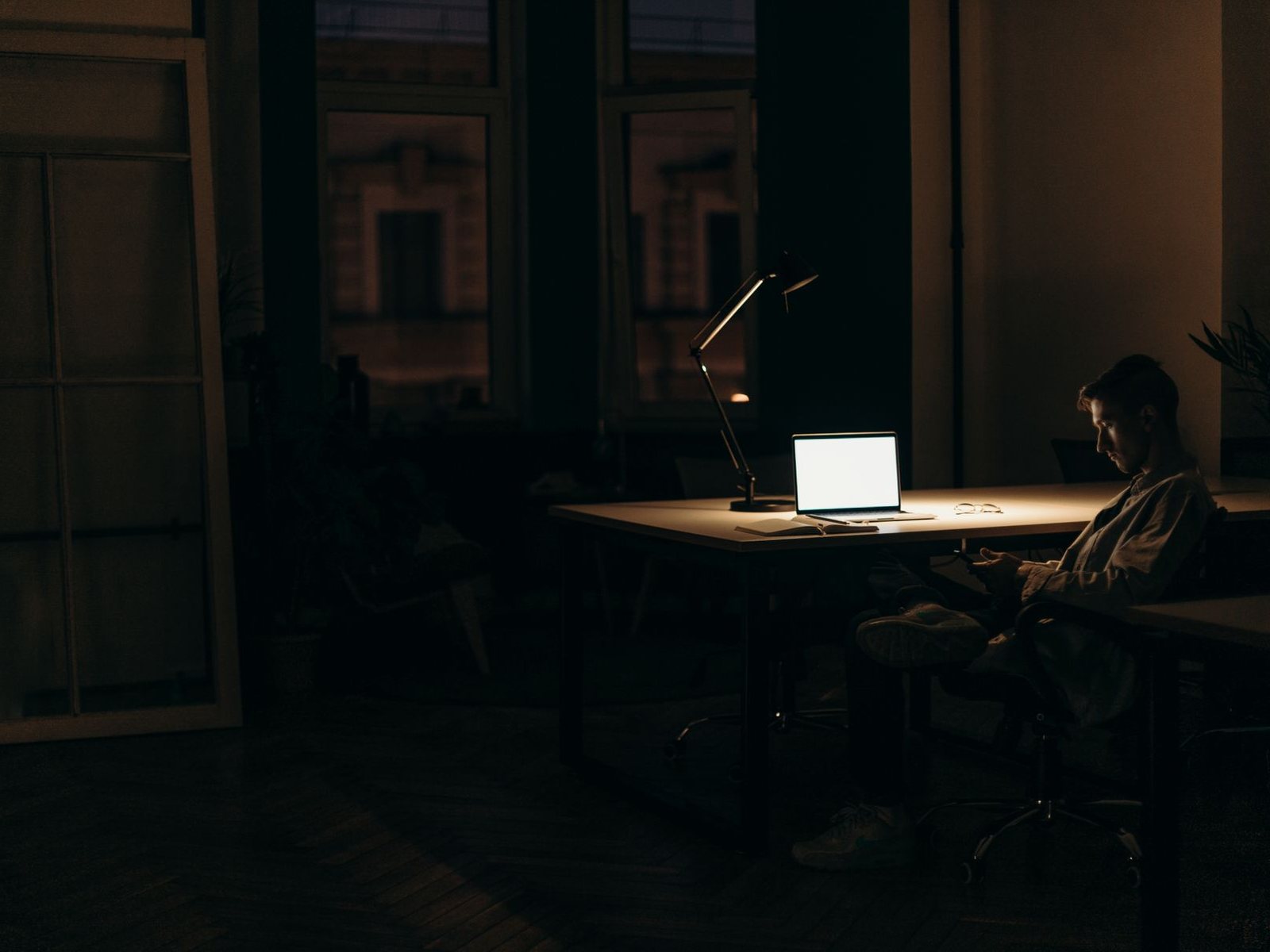 The ALIFY studio at night — a teammate deep in flow, laptop glowing